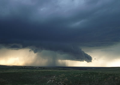 This photograph of a <a
  href="/earth/Atmosphere/clouds/cumulonimbus.html&edu=high">cumulonimbus cloud</a> was taken on the <a
  href="/earth/grassland_eco.html&edu=high">grasslands</a> of eastern Wyoming.
  Notice the <a
  href="/earth/Atmosphere/precipitation/rain.html&edu=high">rain</a> and <a
  href="/earth/Atmosphere/precipitation/hail.html&edu=high">hail</a> falling from this
  cloud! Cumulonimbus clouds form during <a
  href="/earth/Atmosphere/tstorm.html&edu=high">thunderstorms</a>, when very warm, moist air rises into cold air. As this humid air rises, water vapor <a
  href="/earth/Water/condensation.html&edu=high">condenses</a>,
  and forms huge <a
  href="/earth/Atmosphere/clouds/cumulonimbus.html&edu=high">cumulonimbus</a>
  clouds.<p><small><em>         Photo courtesy of <a href="http://www.inclouds.com">Gregory Thompson</a></em></small></p>